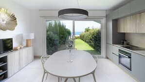 Eine moderne Küche mit Esstisch, Fernseher und Blick ins Freie.