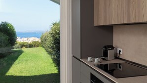 Eine moderne Küche mit Backofen, einer Kaffeemaschine und Blick auf eine grüne Rasenfläche und entfernte Gebäude.
