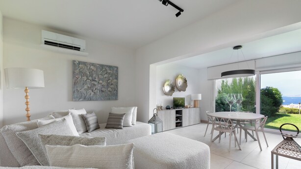 Ein modernes Wohnzimmer mit einer Couch, einem Esstisch und Blick ins Freie.