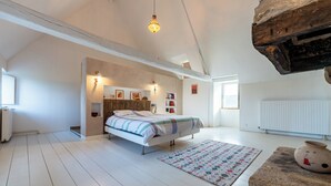 Een slaapkamer met een bed, een vloerkleed, een stenen tafeltje en een hanglamp.