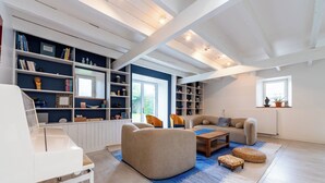 Een moderne woonkamer met een piano, banken, een salontafel en inbouwboekenplanken.