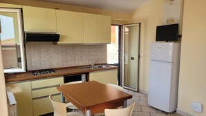 Uma cozinha compacta com mesa e cadeiras, forno embutido e geladeira.