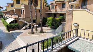 Um edifício residencial com vários andares, um pátio central, uma escadaria e uma varanda com uma mesa estampada.