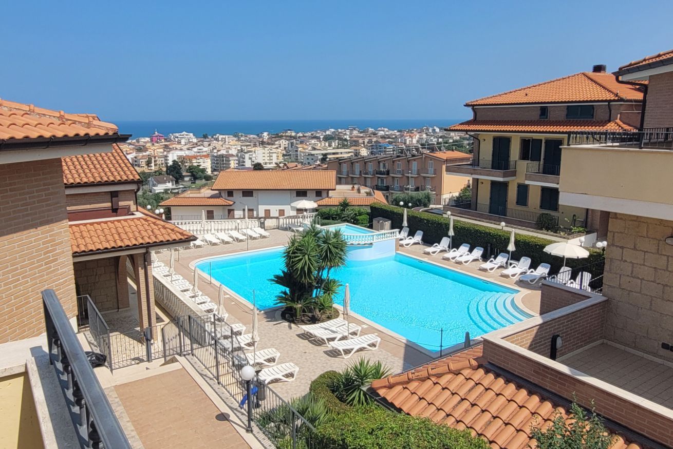 Una piscina en la azotea con tumbonas y vistas al mar.