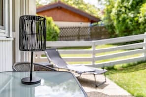 Ein Glastisch mit einer schwarzen Lampe, Sitzgelegenheiten im Freien und einem weißen Geländer.