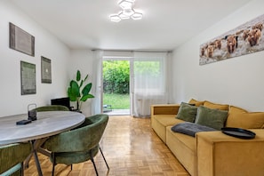 Ein modernes Wohnzimmer mit Essbereich, einem großen Fenster und einem Gemälde an der Wand.