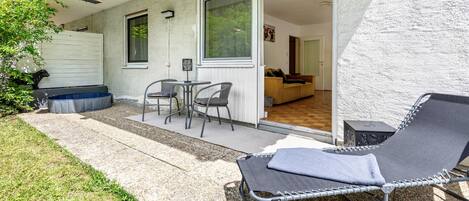 A patio with a lounge chair, a table with chairs, and a sliding glass door leading to an interior room.