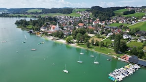 Ein Seeort mit Booten im Hafen, umgeben von Wohnhäusern und Grünflächen.