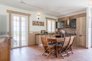 A spacious kitchen with a dining area, large windows, and a brick backsplash.