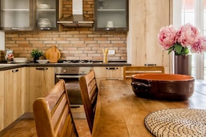 A kitchen with wooden cabinets, a stove, and a dining area with a bench and table.