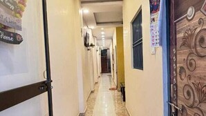 Un pasillo con suelo de baldosas, una puerta decorada y una pared con un cartel.