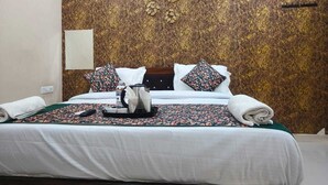 Una habitación de hotel con una cama grande, un cabecero de madera, un pared con diseño de mármol y una mesita de noche con lámpara.