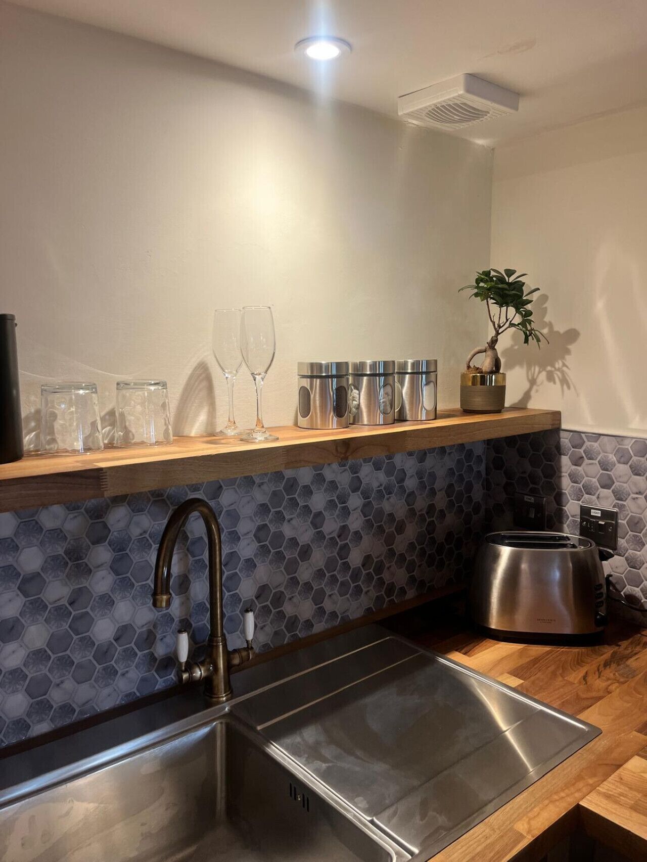 A modern kitchen with a stainless steel sink, a toaster, and a wooden countertop.
