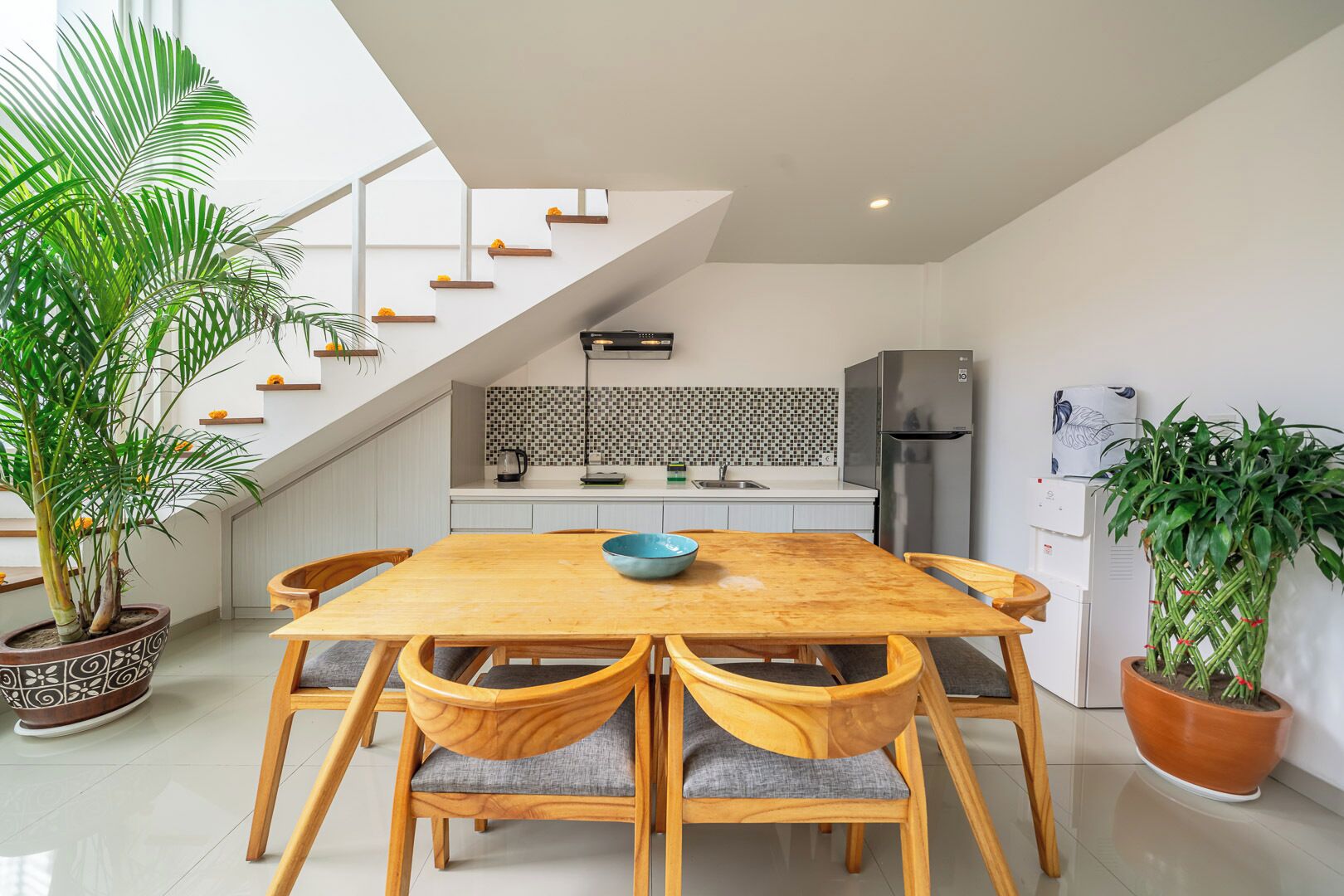 Uma cozinha moderna com uma escada, uma mesa de jantar com cadeiras e plantas em vasos.