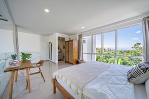 Ein Schlafzimmer mit einem großen Bett, einem Holztisch, einem Stuhl, einem Fenster mit Ausblick und einem Kleiderschrank.