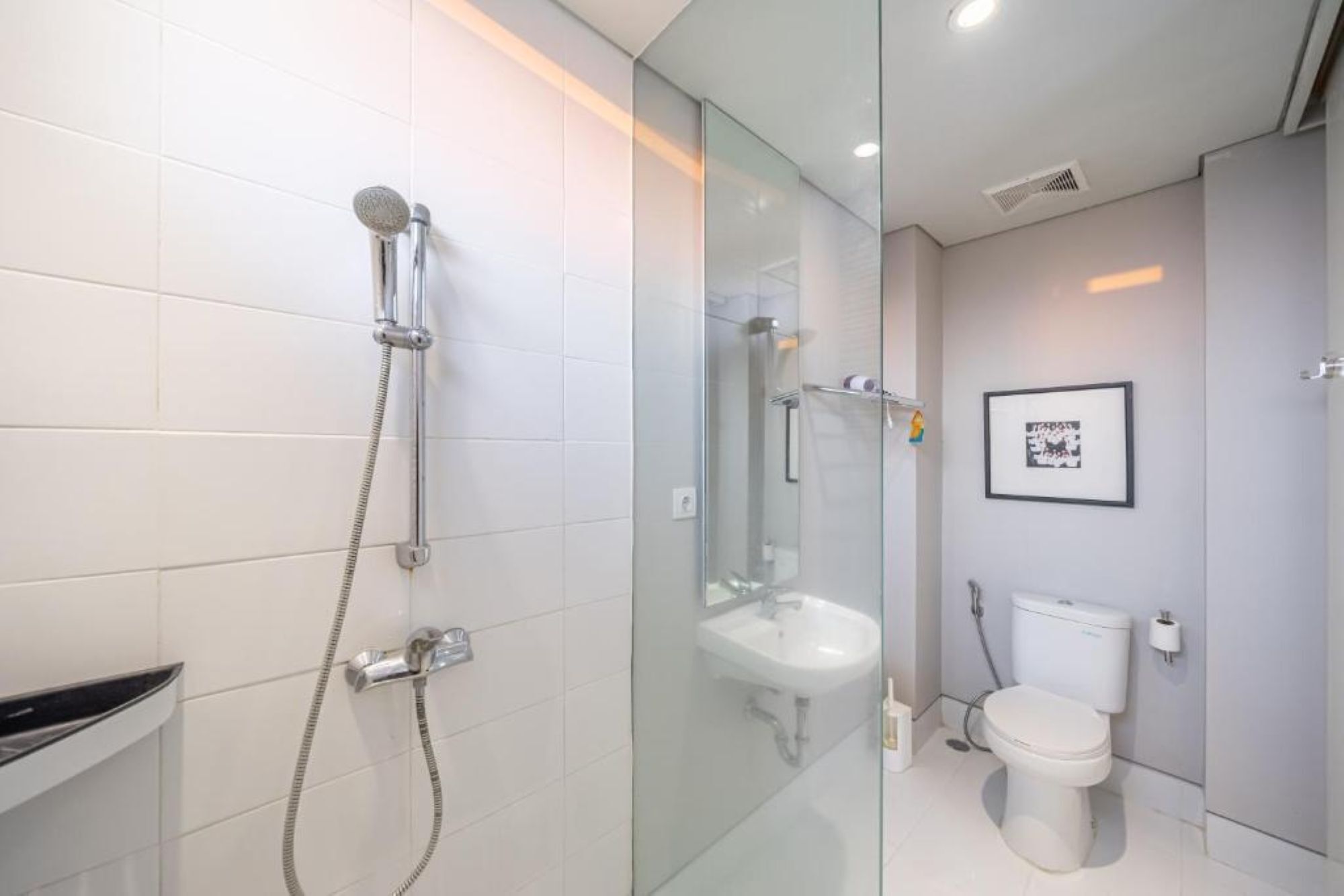 Un baño moderno con cabina de ducha de vidrio, un lavamanos blanco y un inodoro.