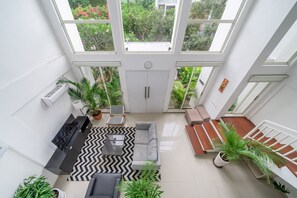 Ein geräumiges Zimmer mit großem Fenster, einer Couch, einem Couchtisch und einem Blumentopf.