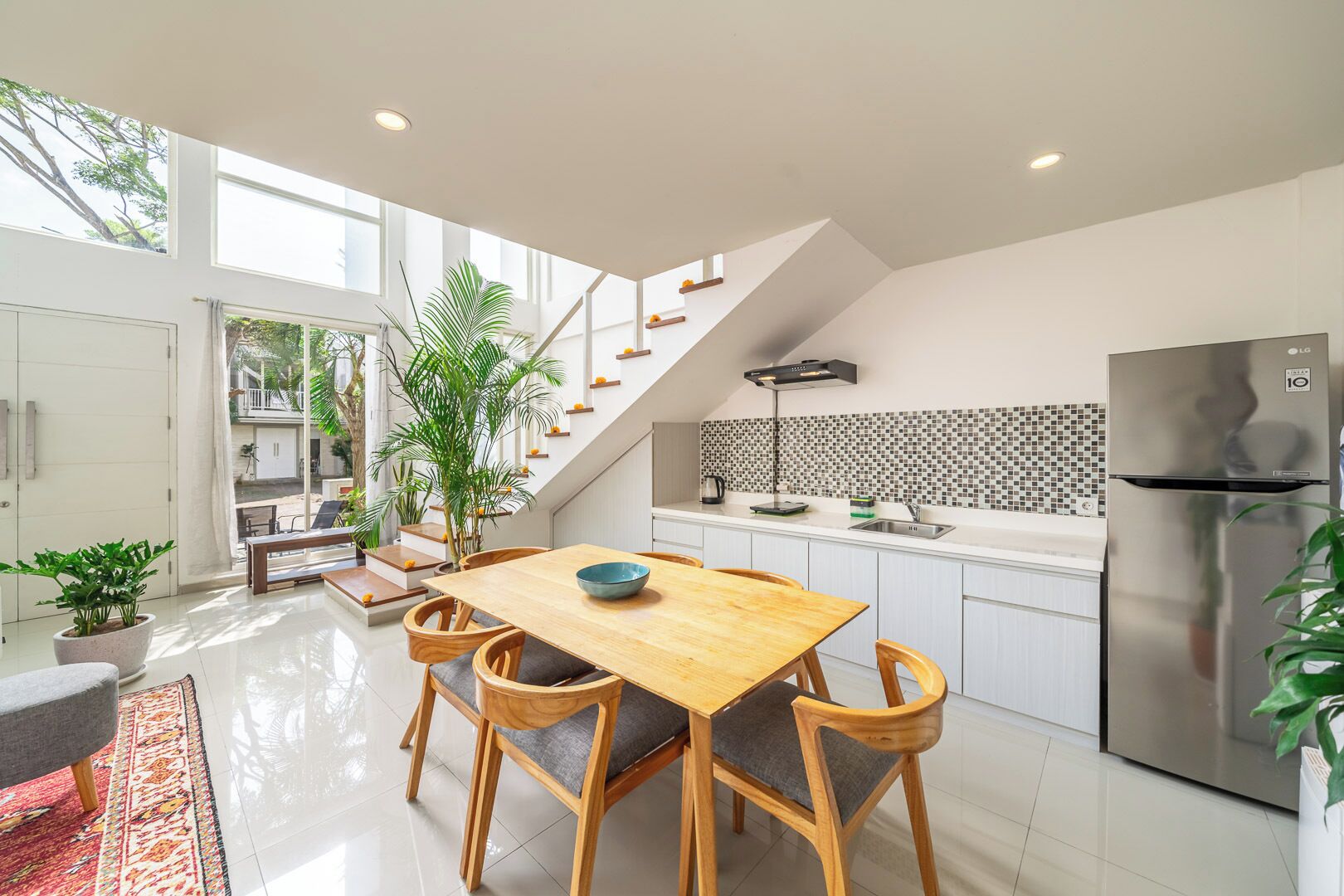 A modern kitchen with a wooden dining table, built-in appliances, and a staircase leading to an upper level.
