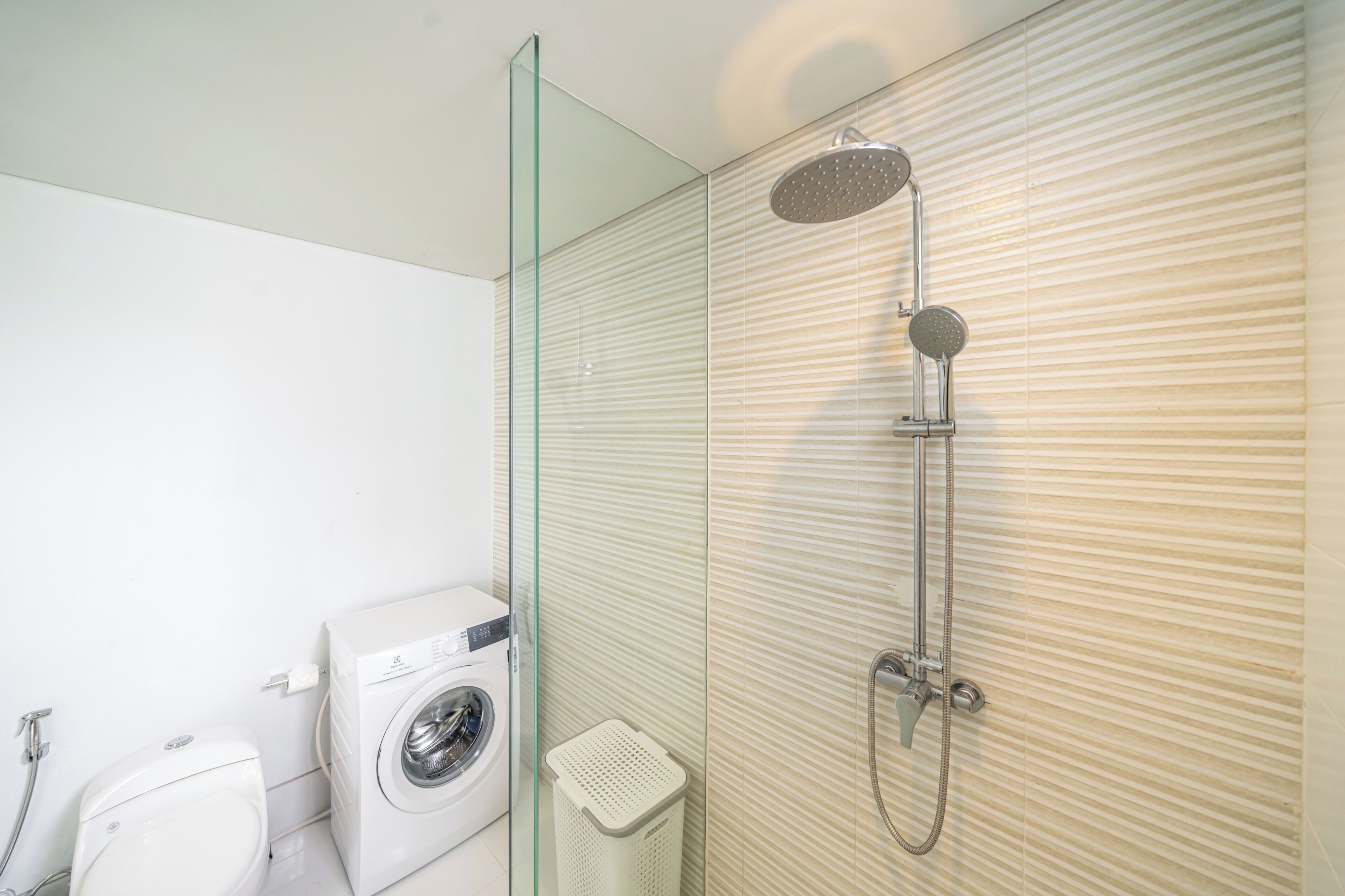 Une salle de bain avec une douche à parois de verre, un lave-linge et des toilettes.