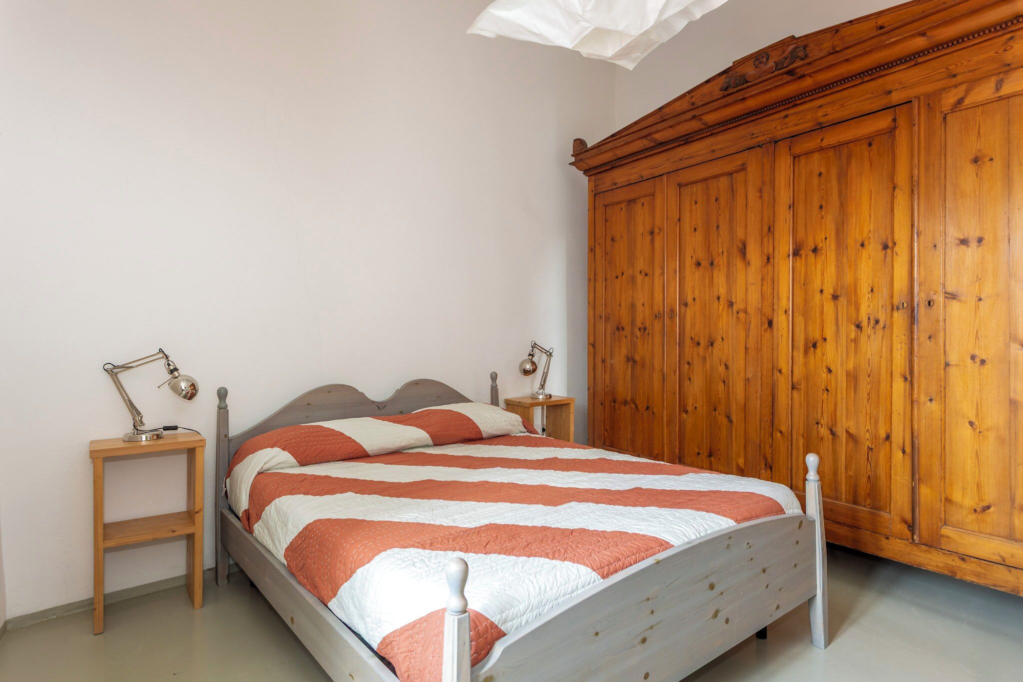 Ein Schlafzimmer mit einem Bett, einem Holzschrank, Nachttischen und Lampen.