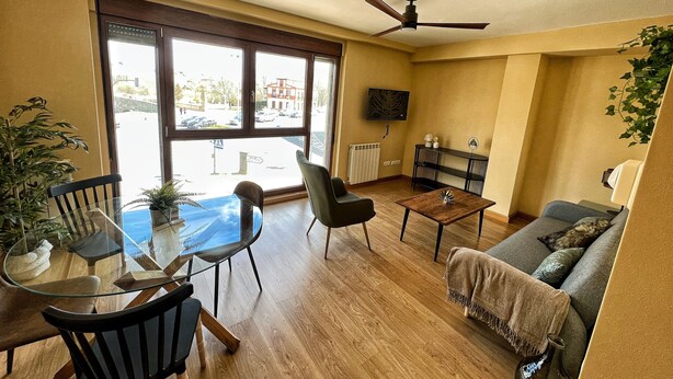A living room with a glass table, chairs, a sofa, a ceiling fan, and a TV on the wall. - 4 Standard. Beautiful 2-bedroom apartment with the best views of Salamanca (Salamanca)