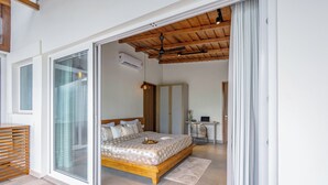 Un dormitorio con cama, ventilador de techo y puerta corrediza de vidrio que da a un balcón.