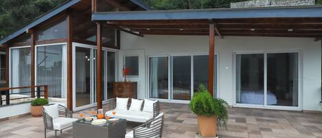A modern house with a patio area featuring outdoor furniture, a dining table, and potted plants.