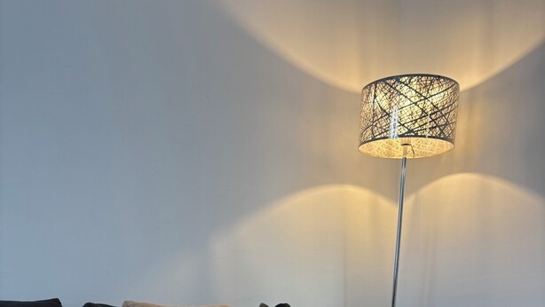 En moderne stue med sofa, gulvlampe, et fad med stearinlys og en dekorativ æske.