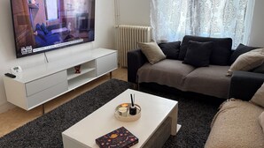 En moderne stue med et fladskærms-tv, en sofa, et sofabord og et tæppe på gulvet.