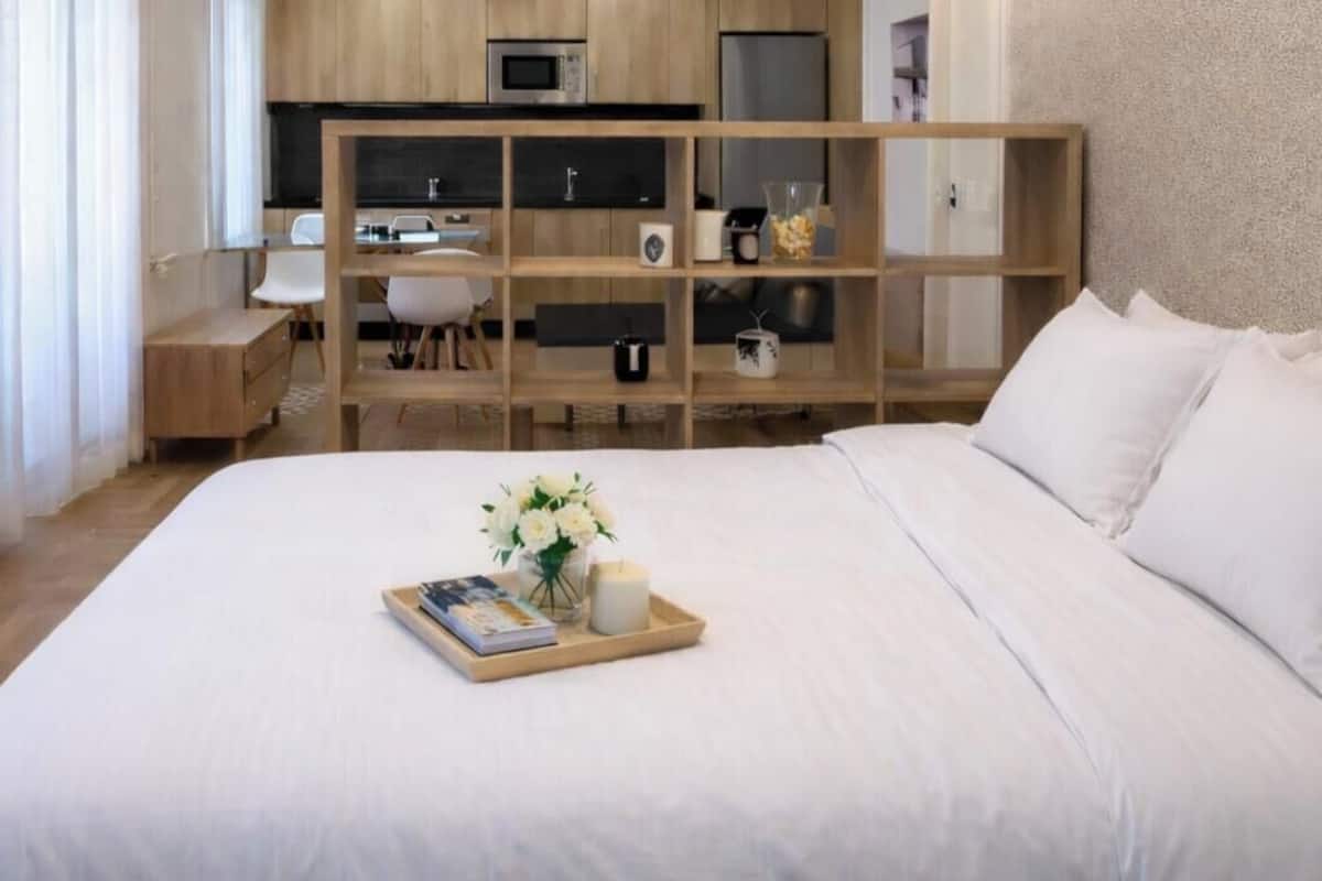 Ein Hotelzimmer mit Bett, Holzschreibtisch, einer Küchenzeile und Blick ins Freie.