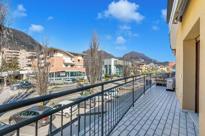 A balcony with a view of a street, buildings, and mountains. - Rosa Apartment, Balcony and AC (Riva del Garda)