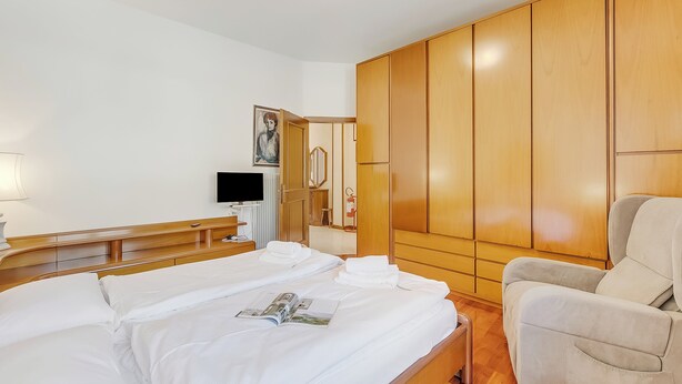 Une chambre d’hôtel avec un lit, une chaise, une télévision et une armoire.