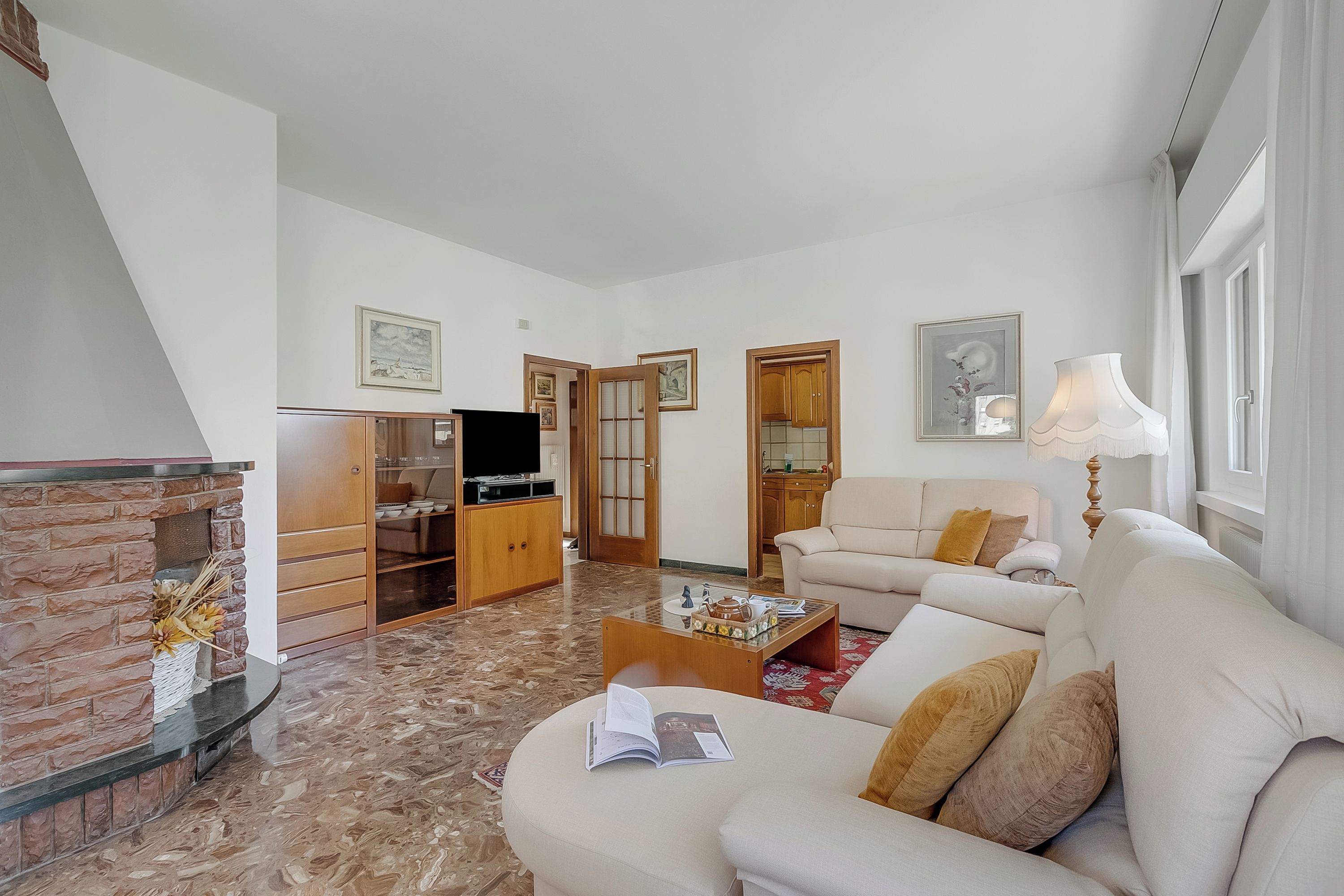 A living room with a sofa, coffee table, fireplace, television, and wooden cabinets.