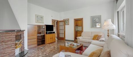 A living room with a sofa, coffee table, fireplace, television, and wooden cabinets.