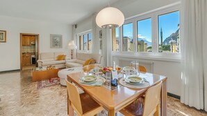Un salon moderne avec un coin repas, de grandes fenêtres et une vue sur les montagnes.