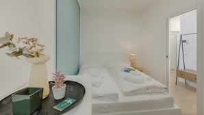 A modern hotel room with a bed, bedside table, lamp, and a potted plant. - Bella Vista Apartment (Riva del Garda)