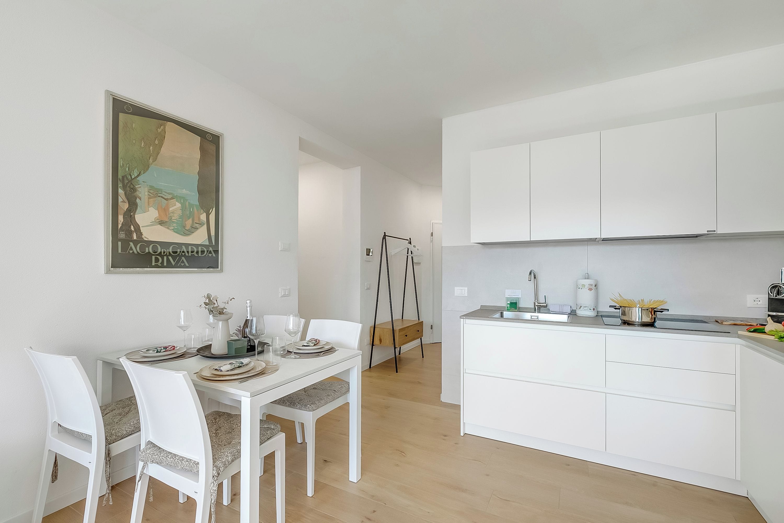 A modern kitchen with white cabinetry, a dining table with chairs, and a hanging chair.