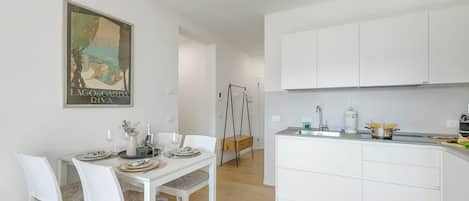 A modern kitchen with white cabinetry, a dining table with chairs, and a hanging chair.
