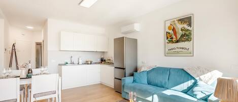 A modern apartment with a dining area, kitchenette, and a blue sofa.