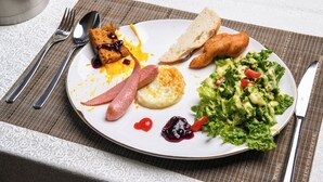 Un plato con diferentes opciones de desayuno, como tostadas, salchicha, huevos y una ensalada.