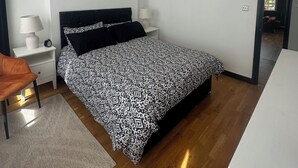 Ein modernes Schlafzimmer mit Bett, Nachttischen, einem Sessel und einem Schreibtisch.