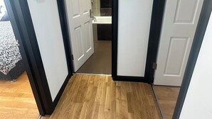 Ein Flur mit Holzboden, weißen Wänden und einer Tür zu einem Badezimmer.