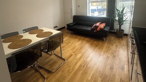 Ein moderner Wohnraum mit Esstisch, schwarzem Sofa und einem Topf mit Pflanze.