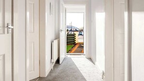 Een hal met witte deuren, vloerbedekking en uitzicht op een straat.