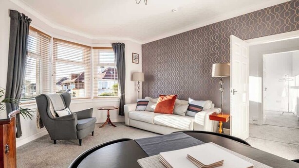 Een moderne woonkamer met een bank, fauteuil en een eettafel met een boek.