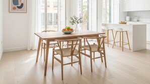 Una cucina luminosa e moderna con mobili bianchi, un tavolo da pranzo in legno con quattro sedie e un'ampia finestra che offre luce naturale.