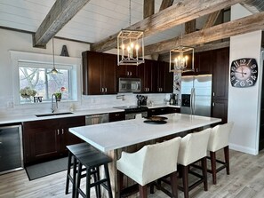 Eine moderne Küche mit dunklen Holzschränken, Edelstahlgeräten und einer großen Kochinsel mit Barhocker.