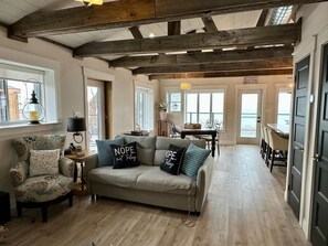 Ein gemütliches Wohnzimmer mit Sofa, Sessel und einem Essbereich mit Tisch und Stühlen.