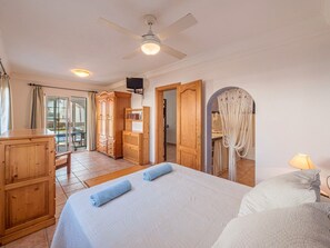 A hotel room with a bed, a wardrobe, a television, and a view of the outside.