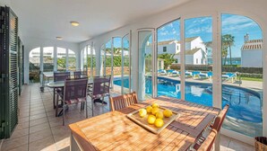 Ein großzügiger Innenbereich mit Pool, einem Esstisch mit Stühlen und Blick auf den Pool.